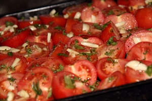 tomato halves with herbs and spices in a roasting pan